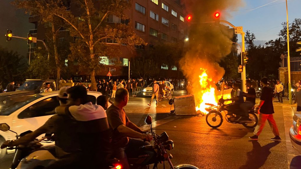 A picture obtained by AFP news agency outside Iran shows protesters gathering around a burning barricade during a protest for Mahsa Amini, a woman who died after being arrested by the Islamic republic's morality police, in Tehran on September 19, 2022.