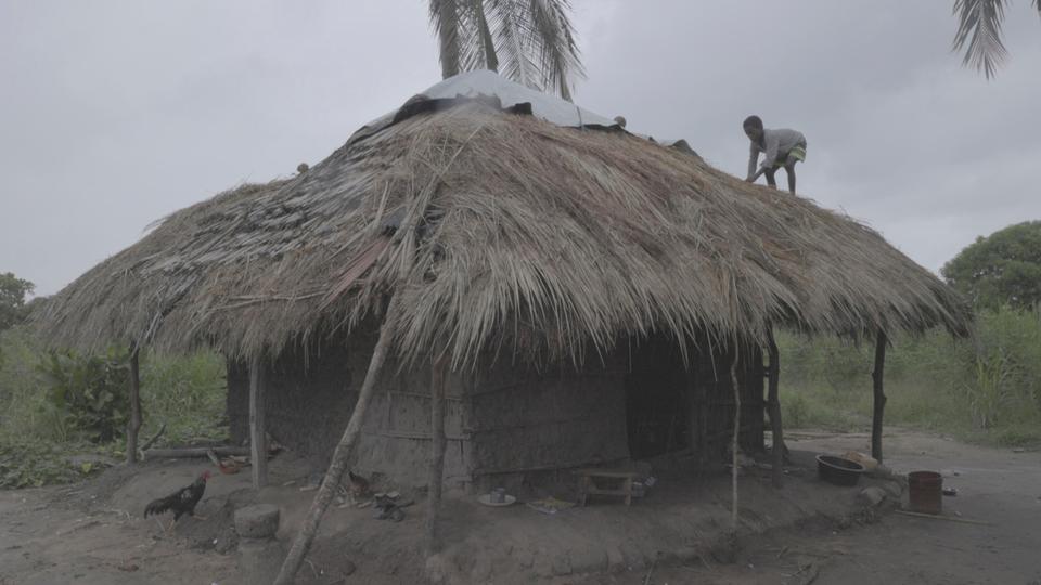 A teenager works on the roof of his house ahead of Storm Freddy, in the Nicoadala district, near Quelimane, in Zambezia.