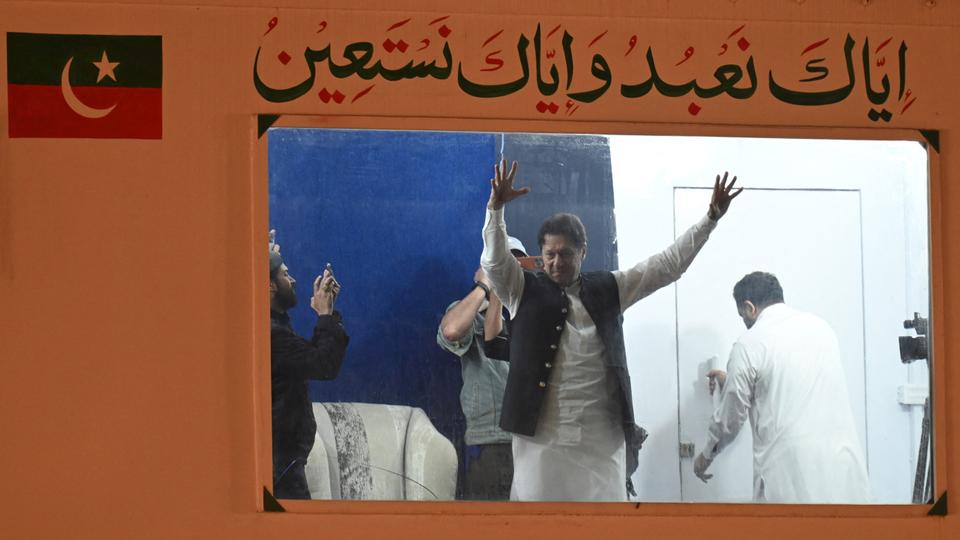 Imran Khan raises hands to his supporters from behind a bulletproof shield on arrival at a rally in Lahore.
