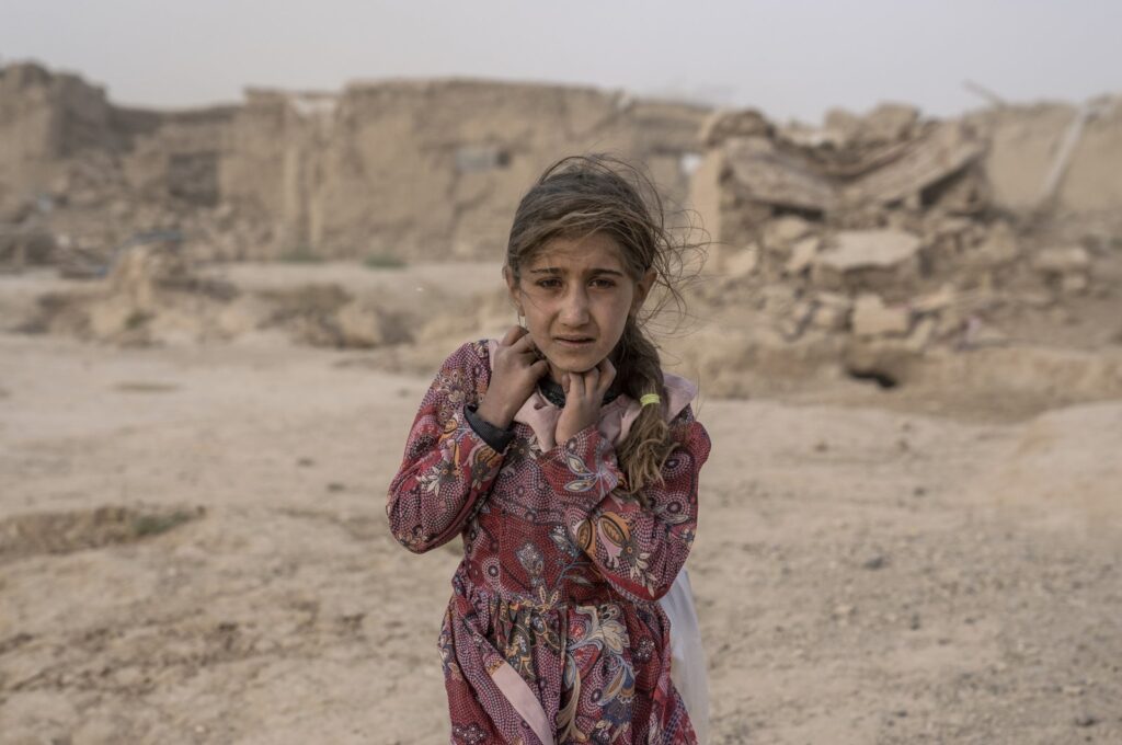 An Afghan girl carries donated aid to her tent, while she is scared from a fierce sandstorm, after an earthquake in Zinda Jan district in Herat province, western Afghanistan, Oct. 12, 2023. (AP Photo)