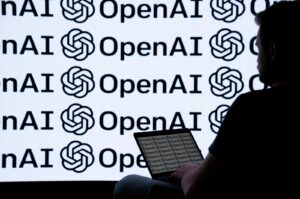 A person is photographed using a device with the backdrop of the OpenAI logo, April 22, 2024. (AA Photo)