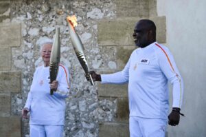 French former football player Basile Boli (R) holds the Olympic Torch and lights up the torch of French founder of Olympique de Marseille supporters club "Dodger's Marseille" Colette Cataldo as part of the Olympic and Paralympic Torch Relays at the Basilica of Notre Dame de la Garde, ahead of the Paris 2024 Olympic and Paralympic Games, Marseille, France, May 9, 2024. (AFP Photo)