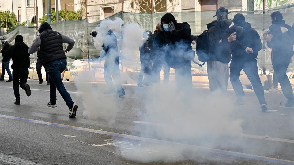 Protesters run from tear gas during clashes with police at a demonstration in Athens on March 5, 2023.